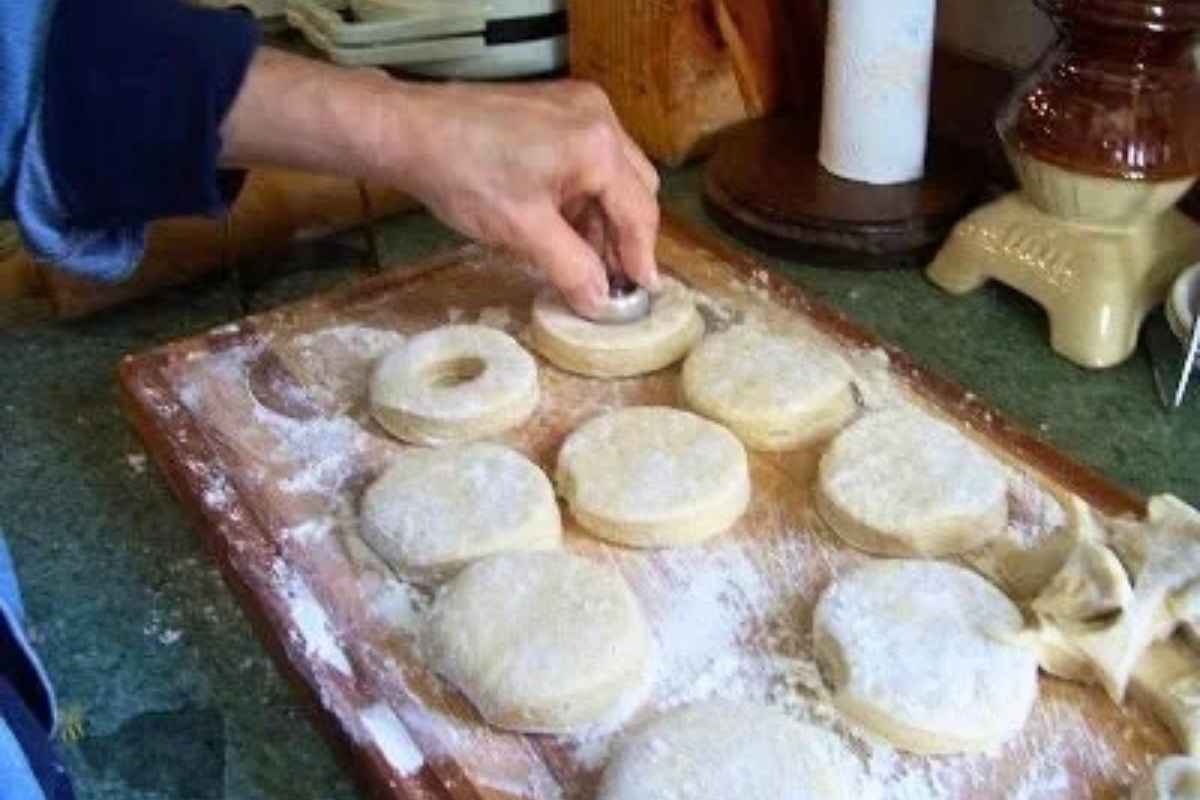 A hand cutting out doughnut shapes.