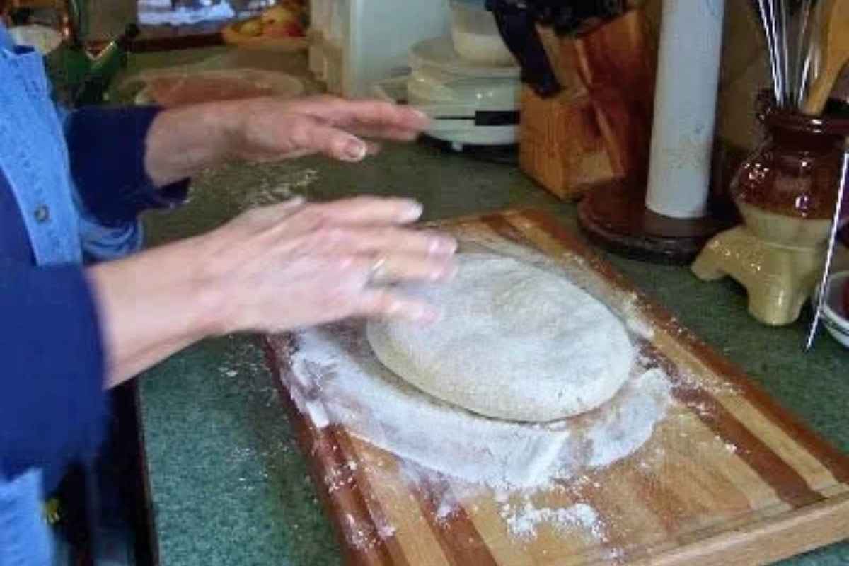 A pair of hands ready to shape the donut dough.