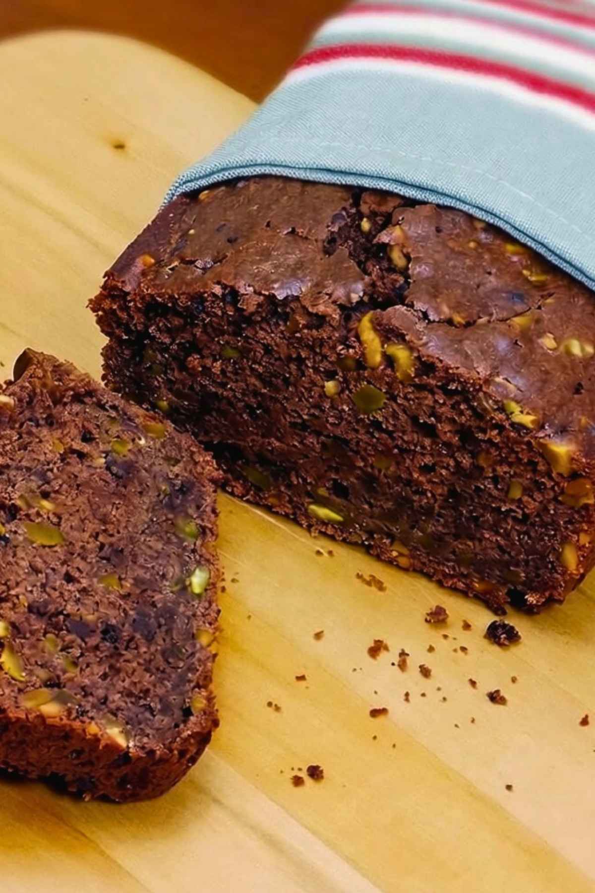 One Chocolate Pistachio Loaf with slices cut away from it showing the crumb of the bread dotted with chopped pistachios.
