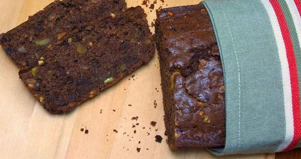 Overhead image of chocolate pistachio bread on a light brown cutting board.