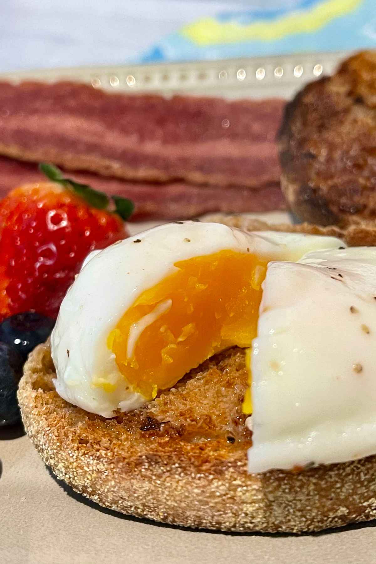 Air Fryer Poached Eggs cut in half on top of english muffin.