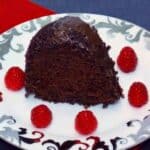 A thick slice of moist Chocolate Kahlua Bundt Cake served on a white plate with fresh raspberry garnish.