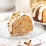 A slice of carrot bundt cake topped with thick cream cheese glaze and chopped pecans.