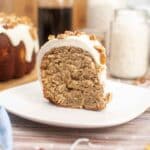 A slice of freshly baked hummingbird bundt cake smothered in rich cream cheese frosting topped with toasted pecans.