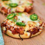 Upclose image of chili lime chicken bagel melt topped with slices of jalapeno and fresh cilantro.