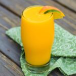 Side view of a frozen mango colada with an orange and lime wheel on top of the glass.