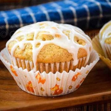 Banana walnut muffin with a white glaze on a wooden tray.