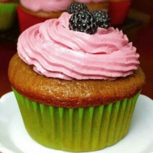 Blackberry Cupcakes with a green cupcake wrapper and blackberry buttercream.