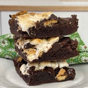 A stack of 3 S'more Brownies on a plage with a green floral napkin in the background.