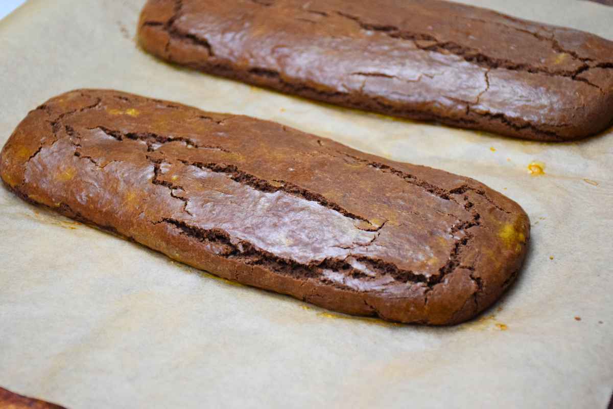 Baked brownie biscotti logs on parchment lined baking sheet.