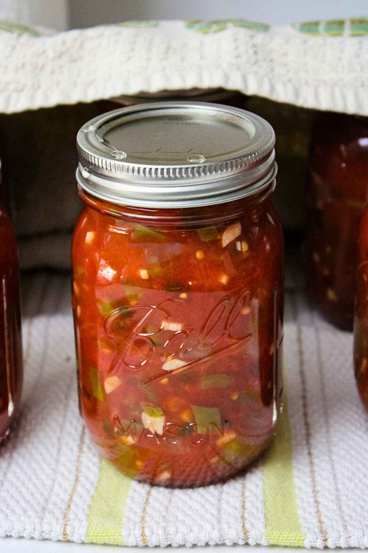 Pint jars of homemade canning salsa on towels.