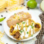 Overhead view of turkey enchiladas with visible filling and refried beans in the background.