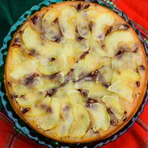 Overhead view of an apple upside down cake baked in a round pan, topped with thinly sliced apples arranged in a spiral pattern and a golden crust.