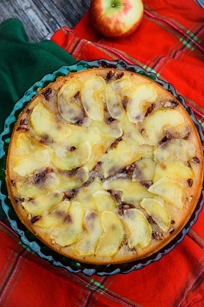 Overhead view of an apple upside down cake baked in a round pan, topped with thinly sliced apples arranged in a spiral pattern and a golden crust.