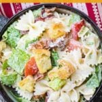 Overhead view of a bowl filled with BLT Pasta Salad made with bowtie pasta, lettuce, tomatoes, bacon, and croutons in a creamy dressing. Text overlay says Fresh, Creamy, Crunchy BLT Pasta Salad with grumpyshoneybunch.com at the bottom.