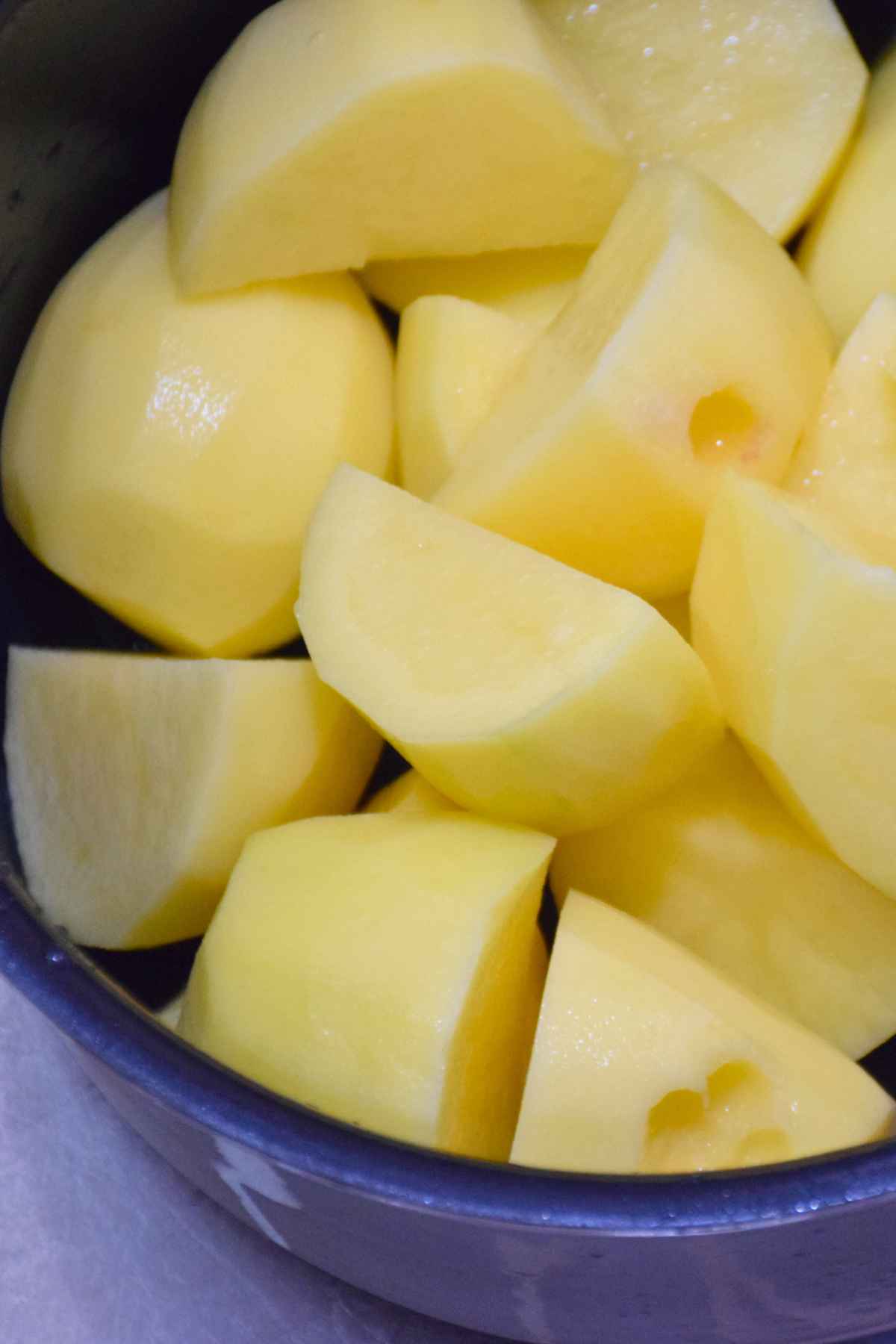 Peeled and quartered yellow potatoes in a pot, ready to be cooked for mashed potatoes.