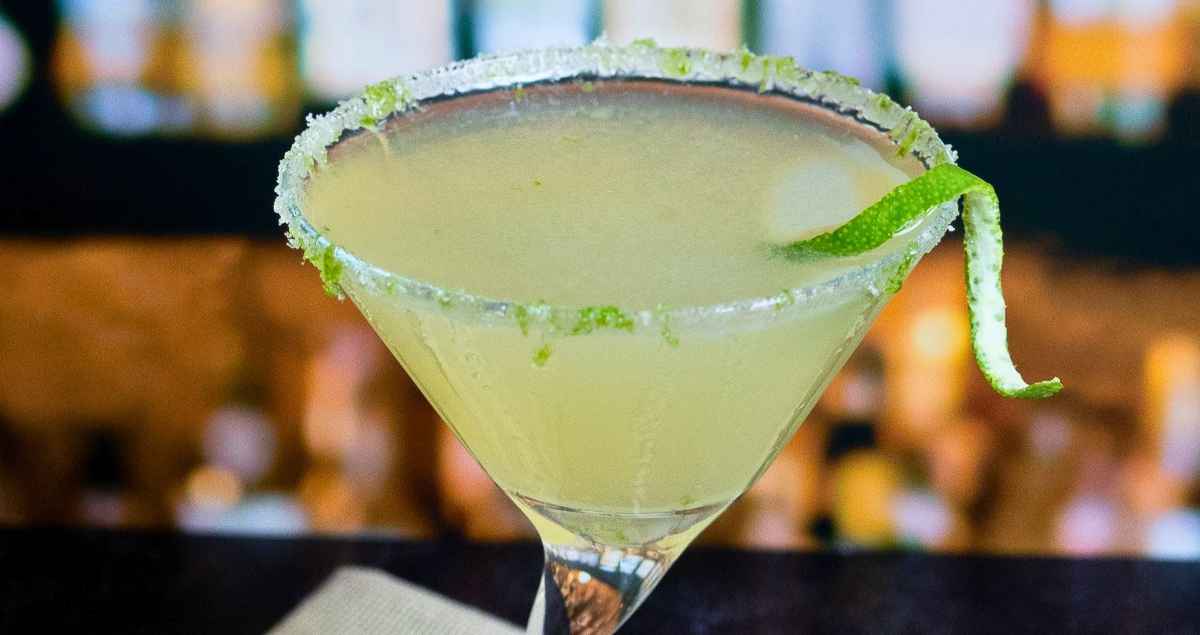 Close up image of a lime drop martini rimmed with sugar and lime zest.