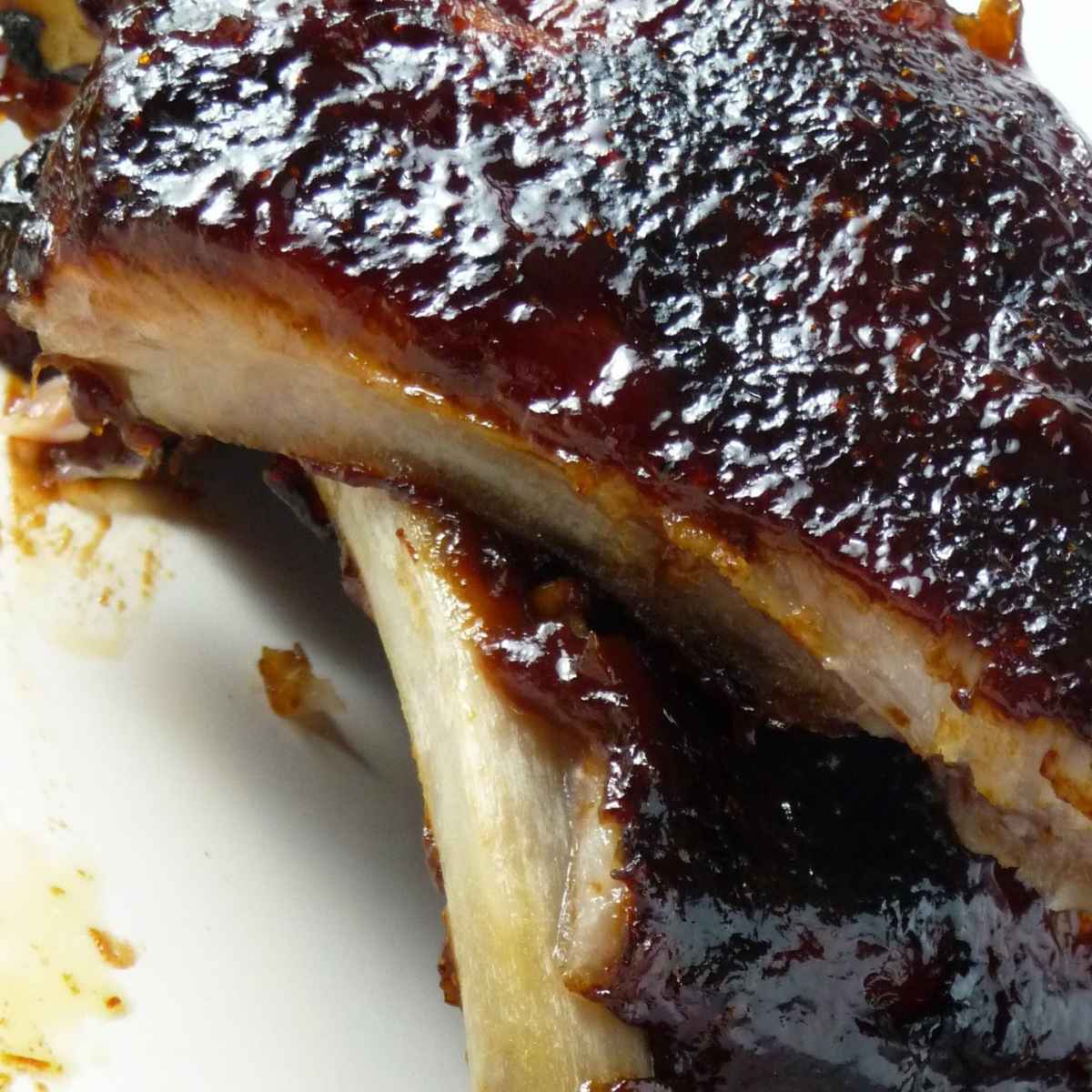 A close up of sliced rib showing the tender meat and caramelized barbecue glaze.