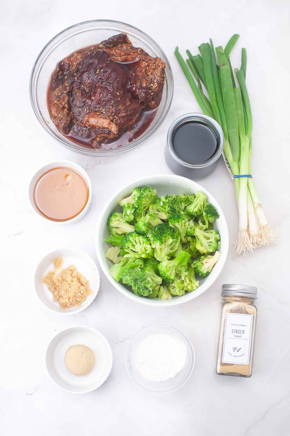 Flat lay of ingredients, including marinated beef, broccoli, green onions, soy sauce, minced garlic, ground ginger, and cornstarch.