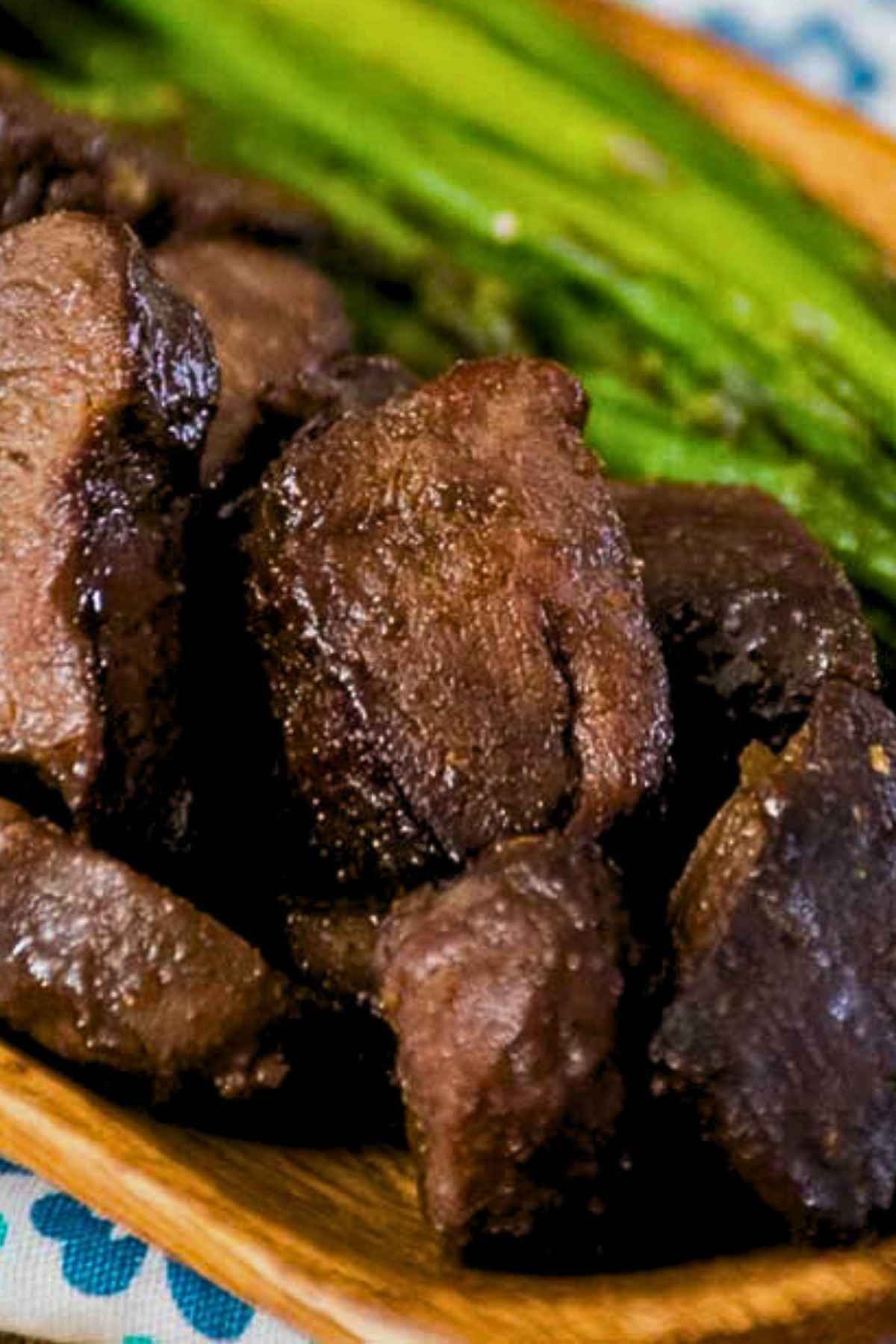 Close-up view of juicy, browned venison steak bites after air frying, served with roasted asparagus.