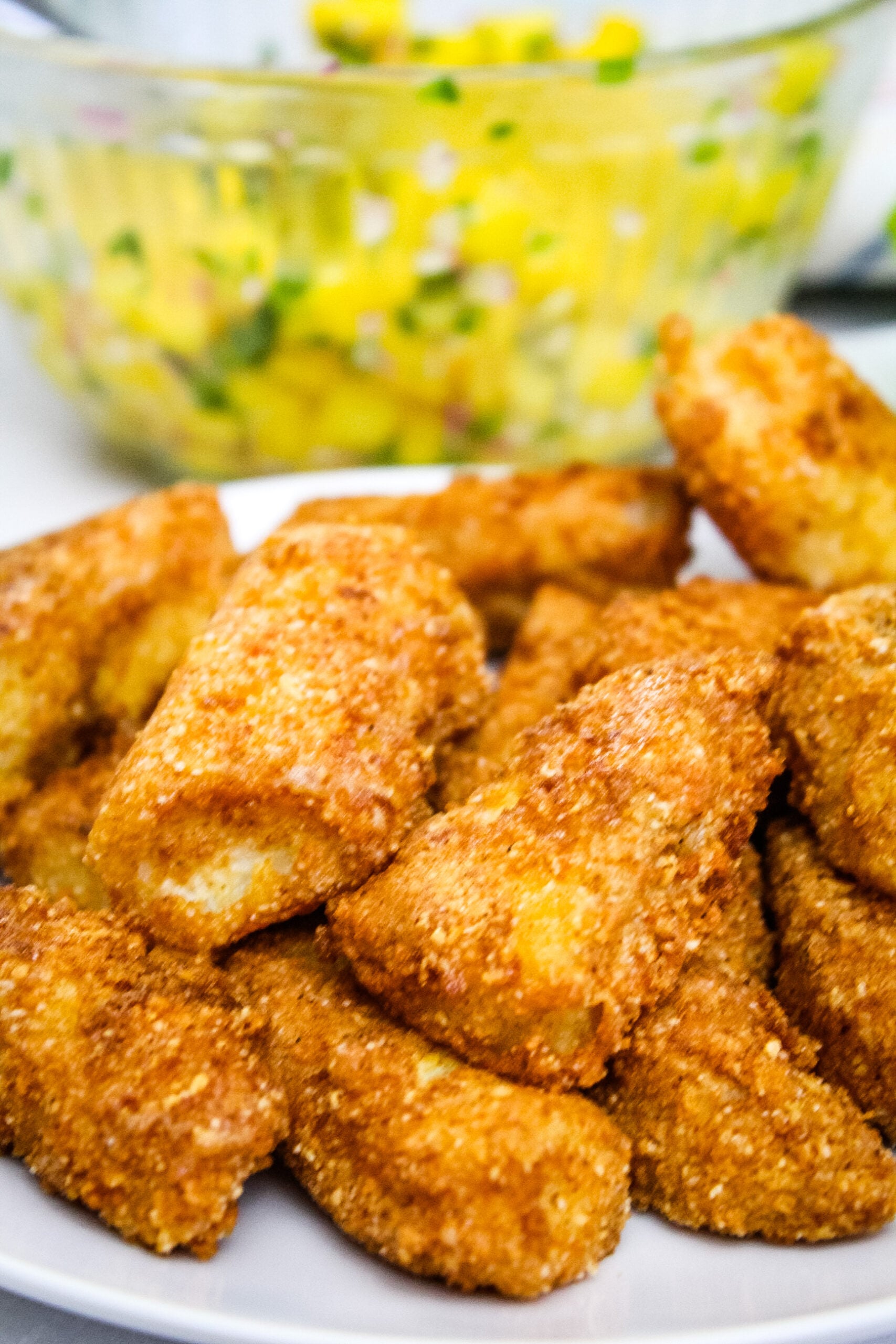 Golden Brown Gluten Free Fish Sticks piled on a white plate, showcasing their crispy almond flour breading.