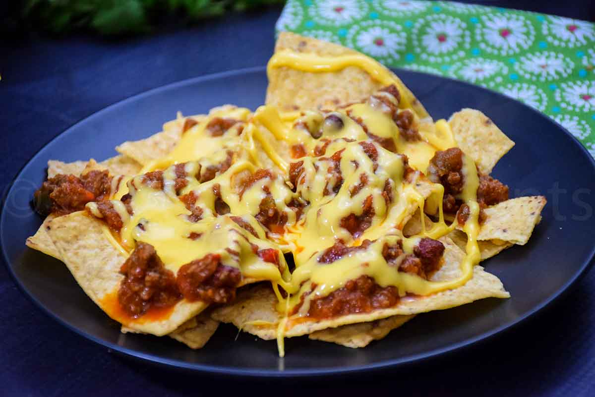 A plate of tortilla chips topped with chili and melted cheese.