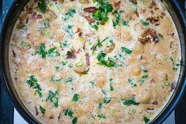 A bubbling skillet of creamy Cajun shrimp sauce with pieces of shrimp, crispy bacon, fresh herbs stirred into the rich, seasoned base.