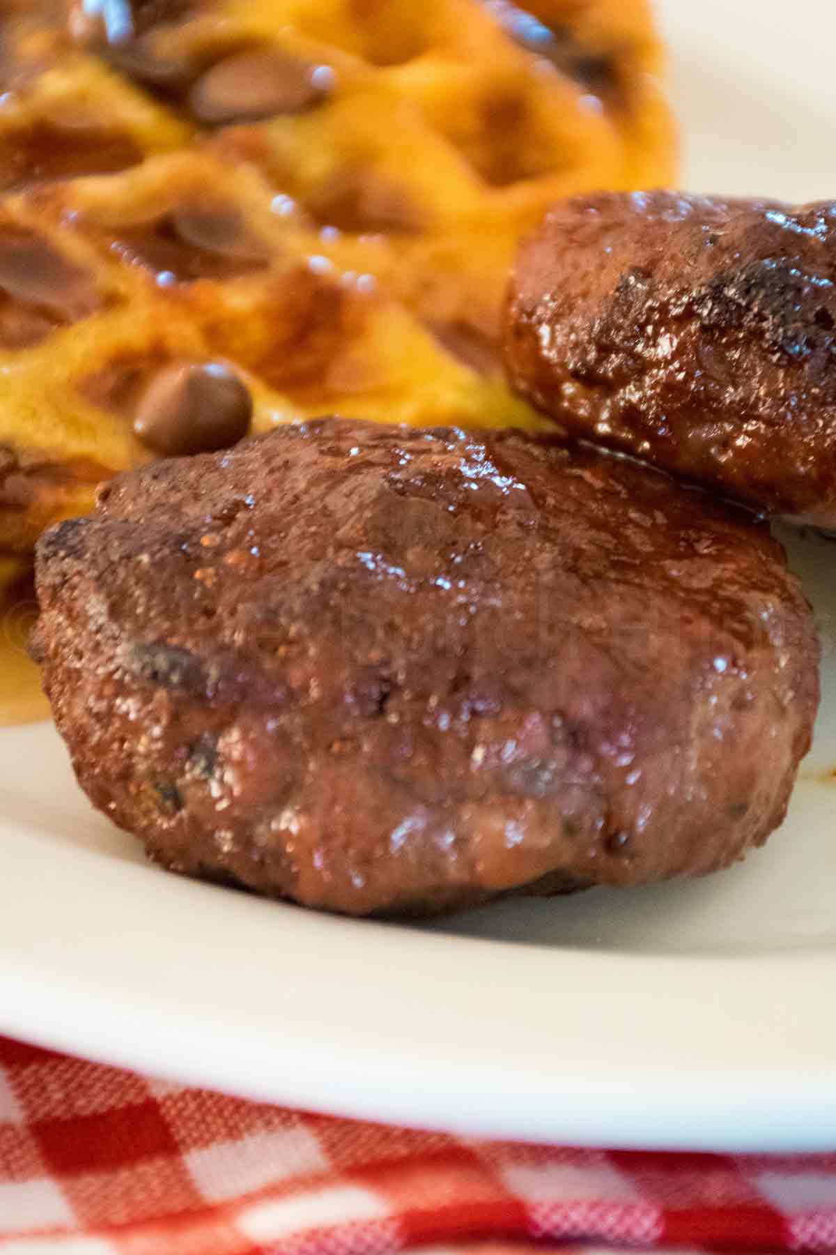 Close up of two air fried venison breakfast sausage on a white plate.