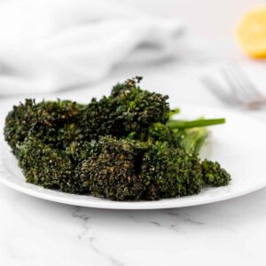 Plated serving of crispy air fryer broccolini on a white dish.