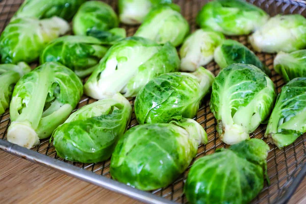 Fresh cooked and lightly seasoned brussels sprouts arranged on an air fryer rack.