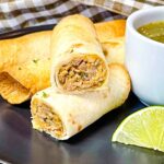 Crispy pulled pork taquito cut open to show shredded pork filling with cilantro garnish.
