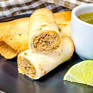 Crispy pulled pork taquito cut open to show shredded pork filling with cilantro garnish.