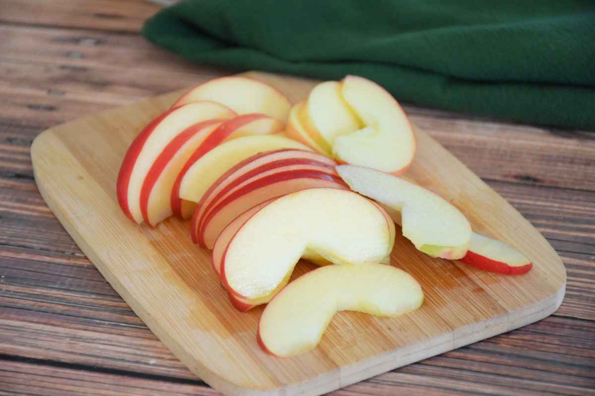 Sliced fresh red apples arranged on a small wooden cutting board.