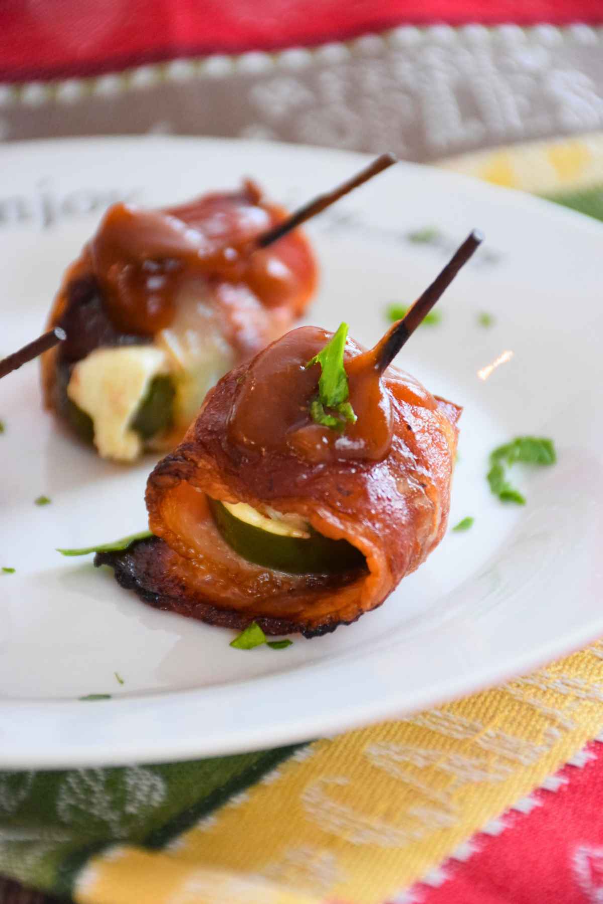 Bacon wrapped venison bites topped with barbecue sauce on a white plate.