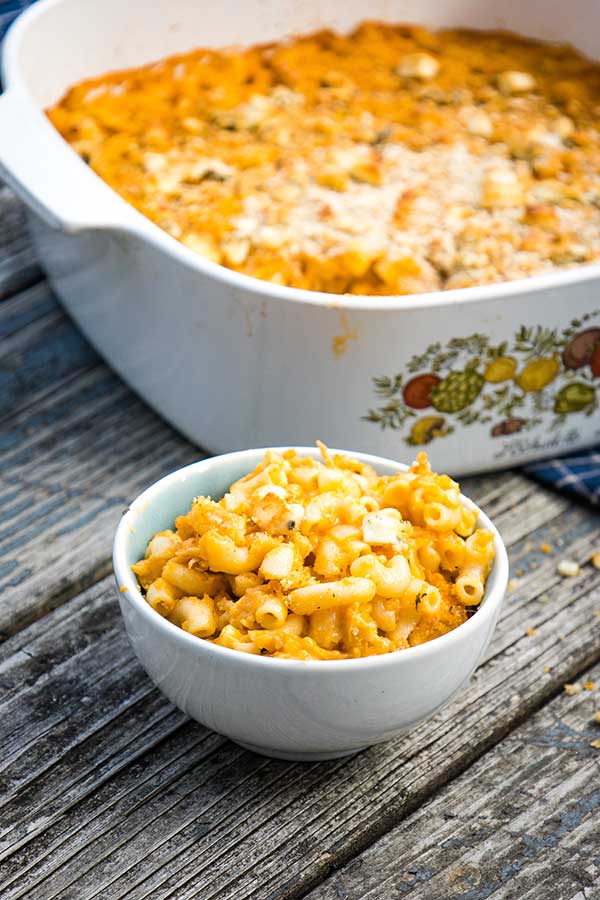 A bowl of buffalo chicken macaroni and cheese with a large casserole in the background.