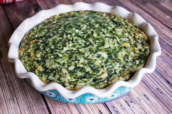Whole baked crustless quiche in a scalloped ceramic pie dish.