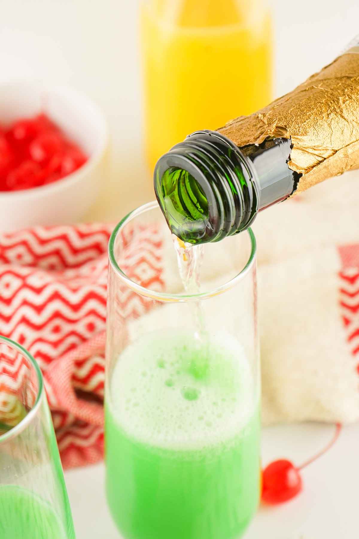 Bubbly Champagne being poured into a Grinch Mimosa.