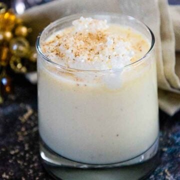 Glass of homemade eggnog topped with whipped cream and a sprinkle of nutmeg.