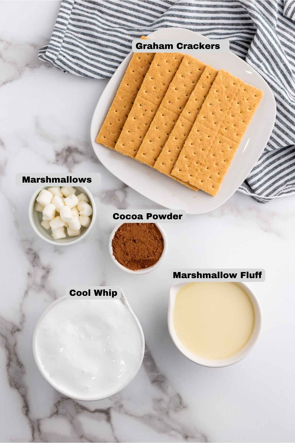 Overhead view of ingredients including graham crackers, marshmallows, cocoa powder, marshmallow fluff, and cool whip.