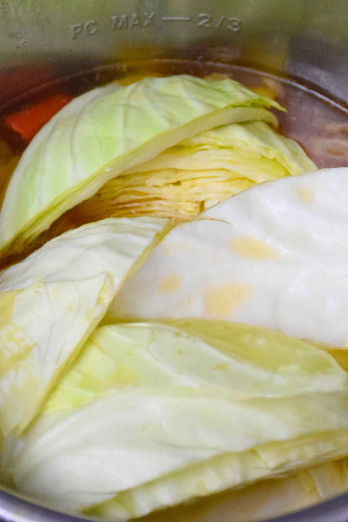 Cabbage wedges cooking in broth inside an instant pot.