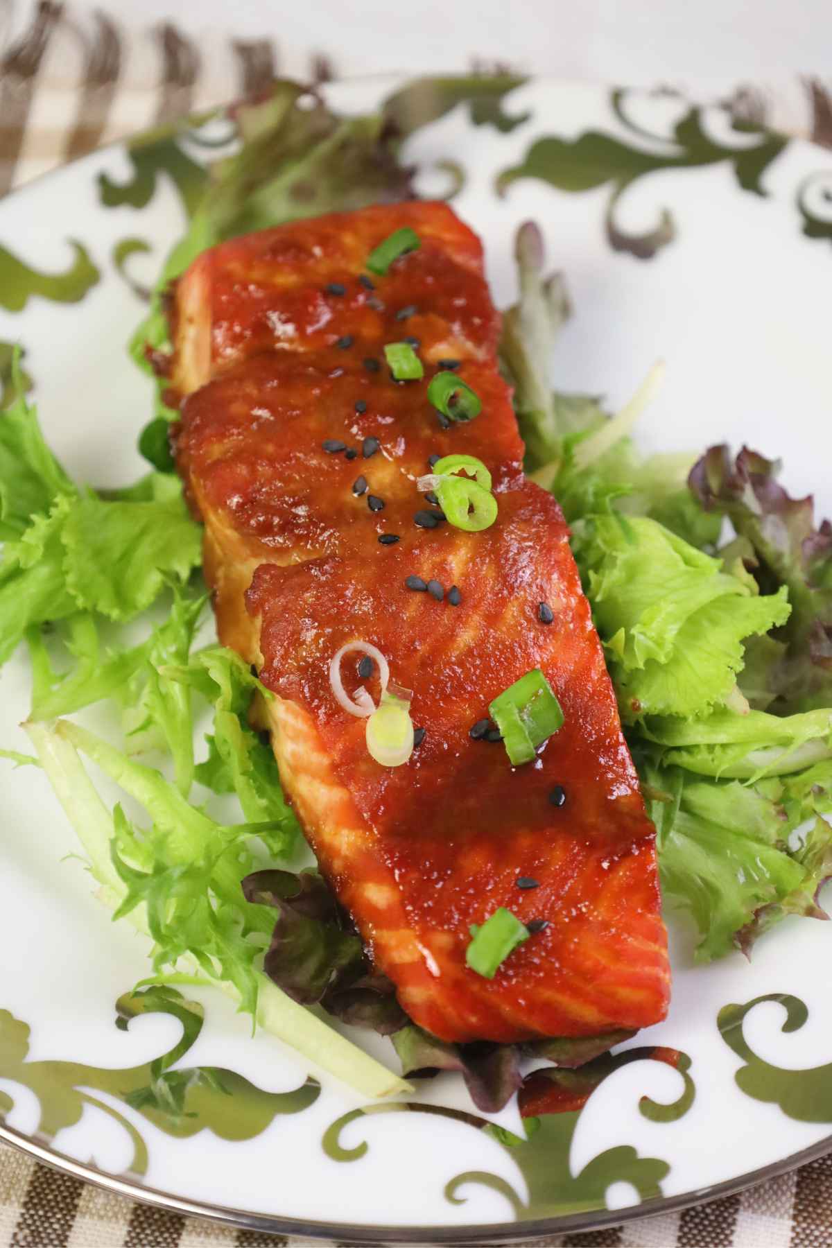 Overhead view of miso maple salmon served on mixed greens and garnished with scallions.