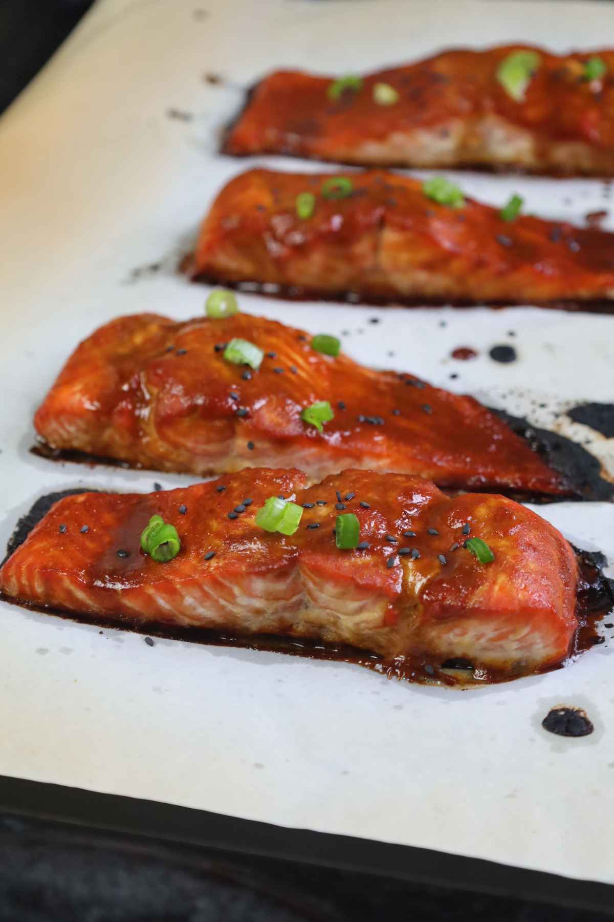 Baked miso maple salmon fillets on a parchment lined baking sheet.