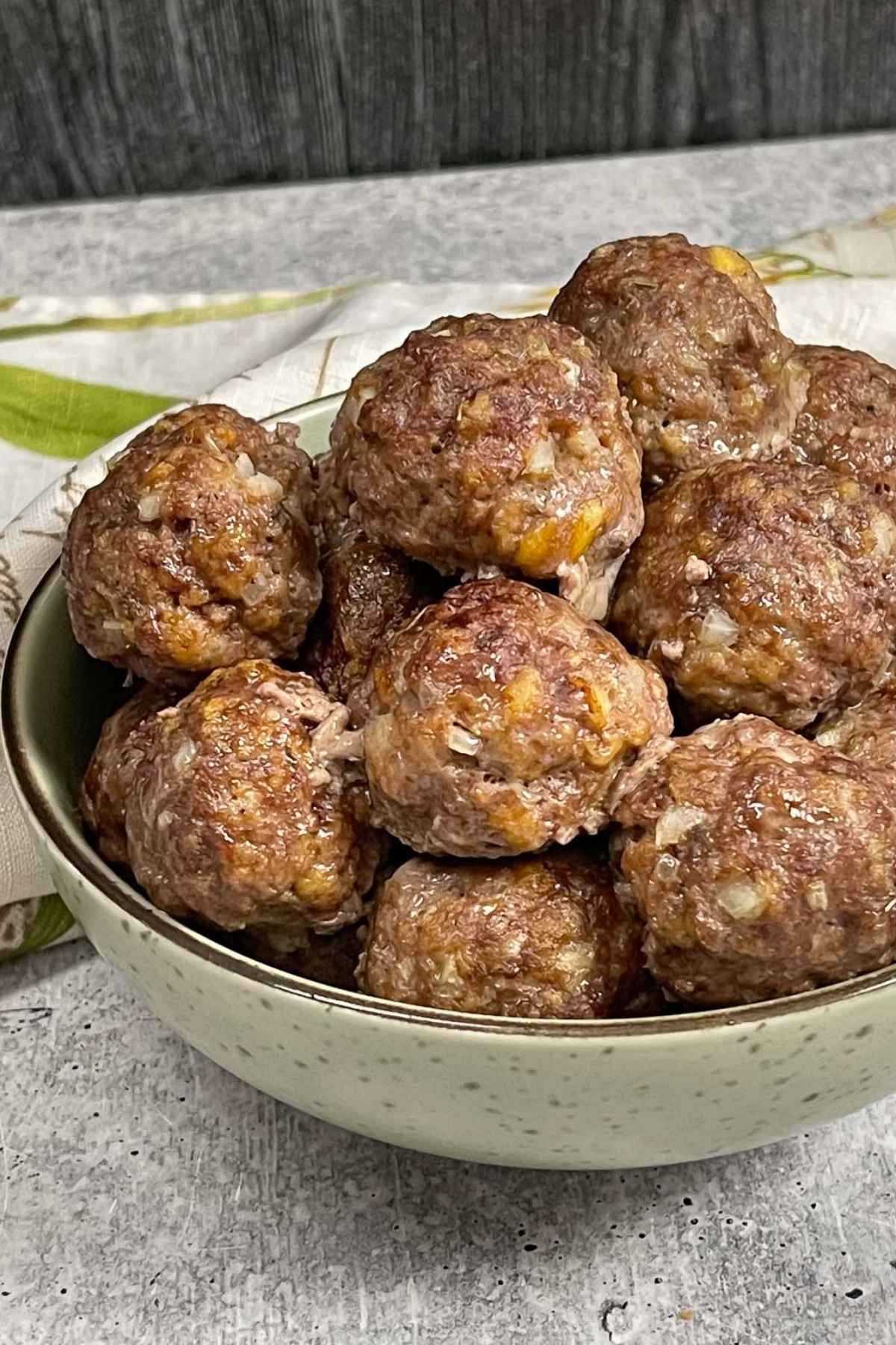 Bowl of juicy oven baked meatballs with onions and cheese, ready to serve as a main dish or appetizer.