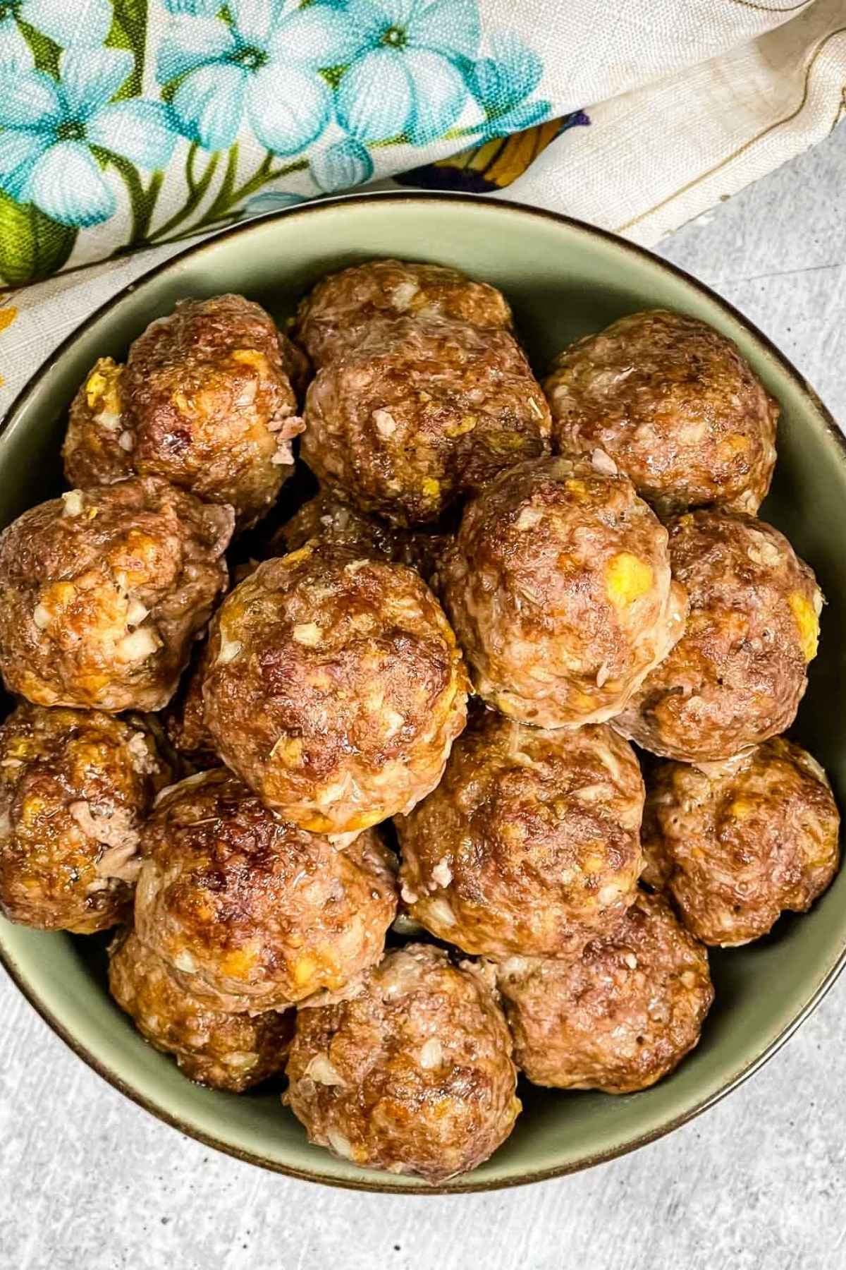 Bowl of juicy oven baked meatballs with onions and cheese, ready to serve as a main dish or appetizer.