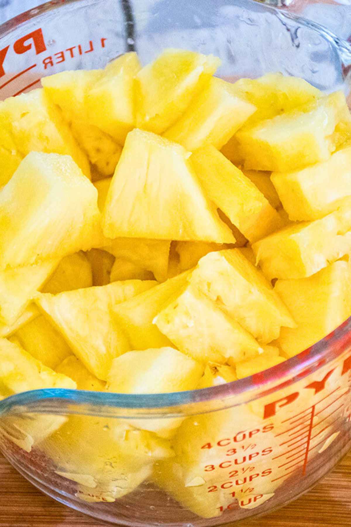 Fresh pineapple chunks in a glass measuring cup.