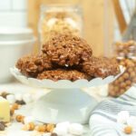 A stack of homemade Star Crunch cookies made with chocolate, marshmallows, and crispy rice cereal, displayed on a white pedestal stand.