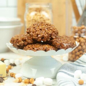 A stack of homemade Star Crunch cookies made with chocolate, marshmallows, and crispy rice cereal, displayed on a white pedestal stand.