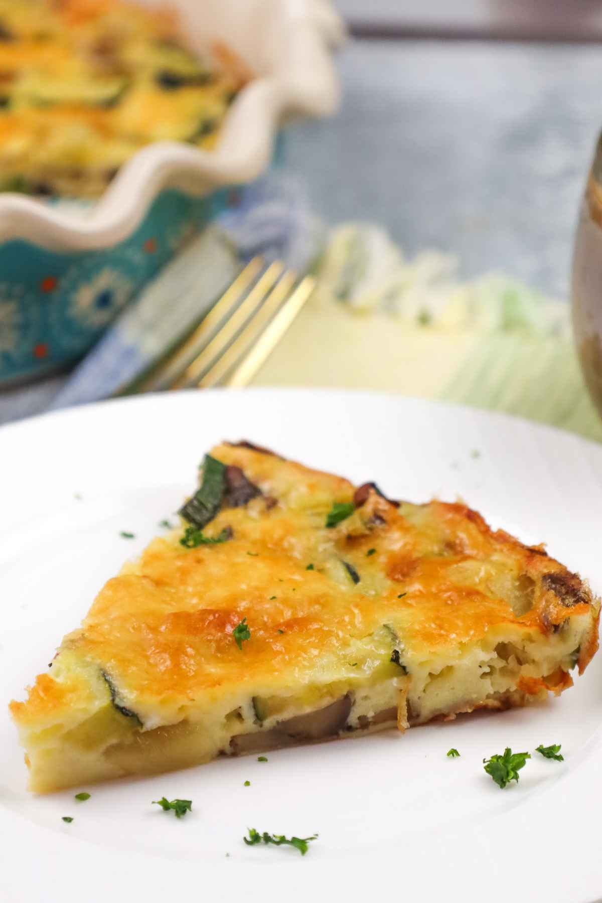 Slice of roasted zucchini mushroom quiche on a plate showing creamy vegetable filling.