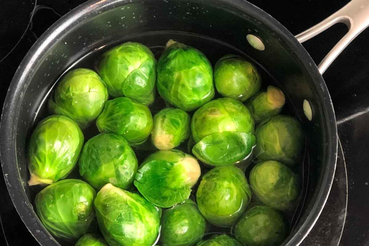 Saucepan with parboiled brussels sprouts on a burner.