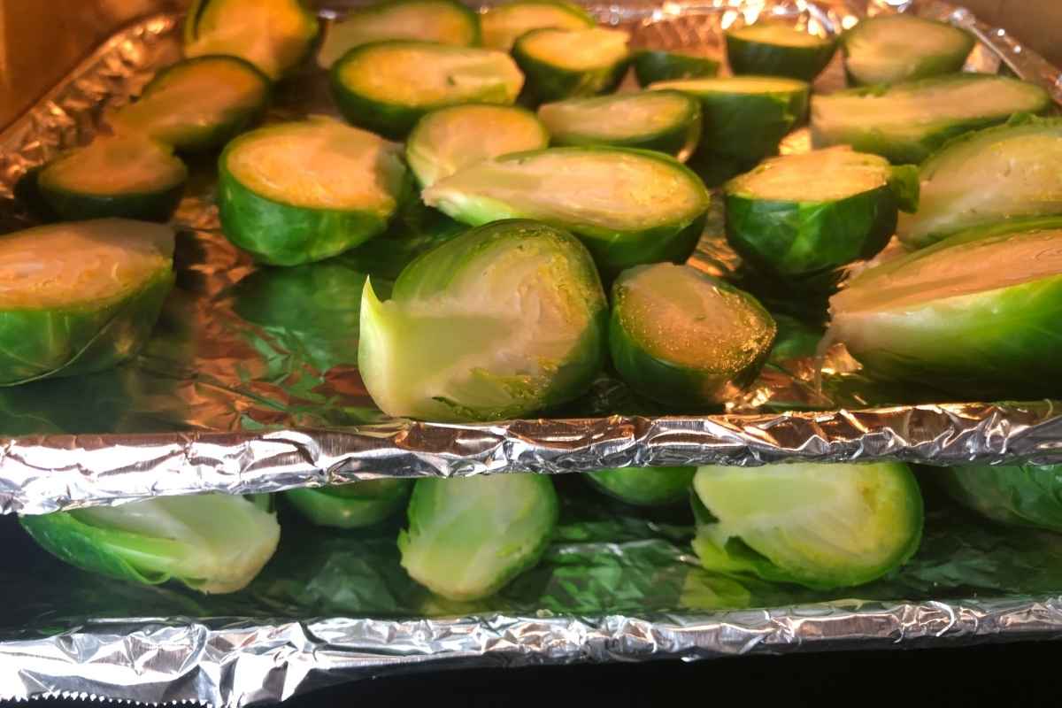 Halved brussels sprouts on a foil lined tray in an air fryer oven.